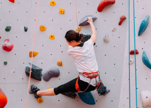 Woman scaling indoor rock climbing wall